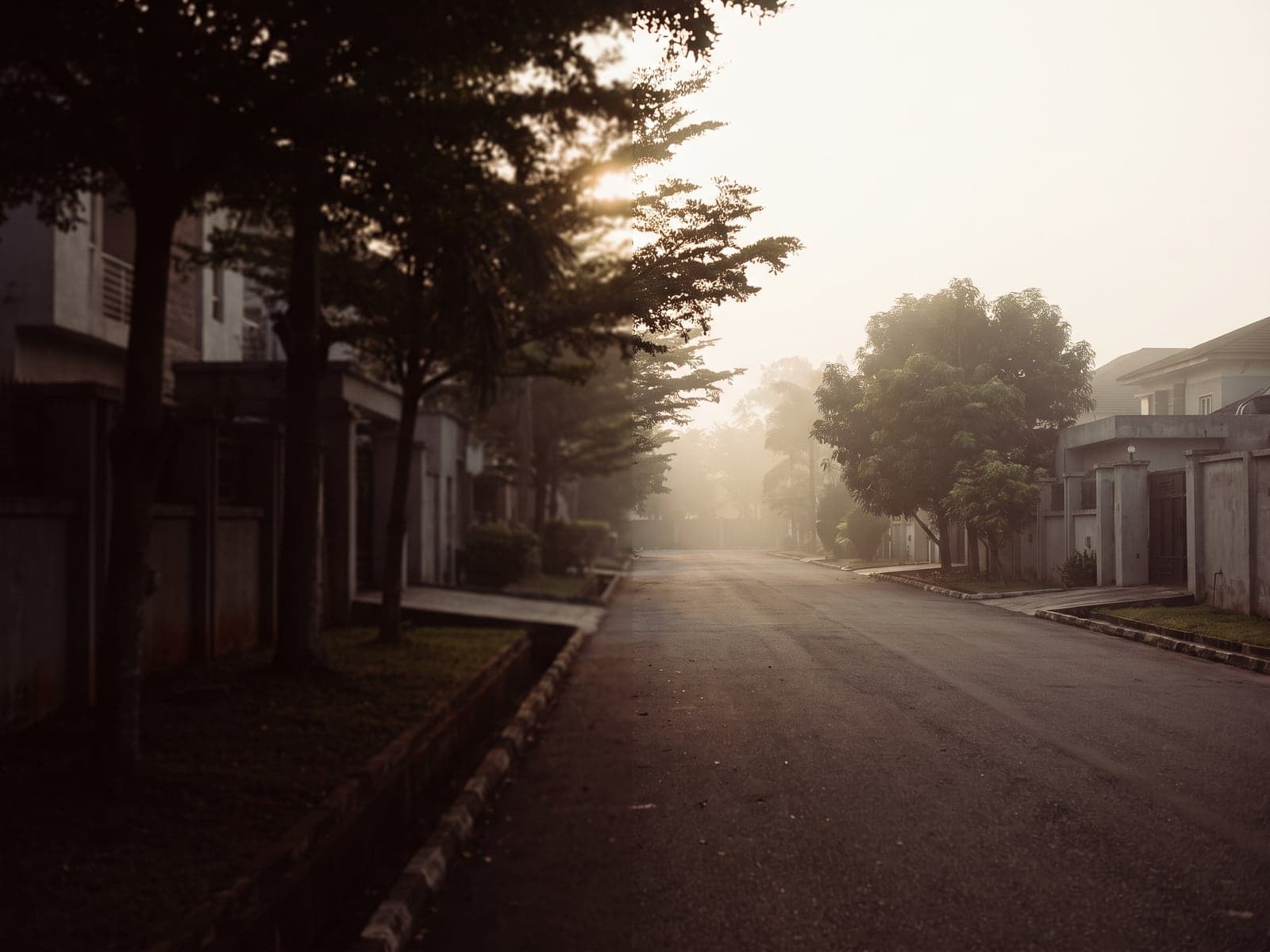 A quiet estate road in Enugu with low buildings and trees in early morning light